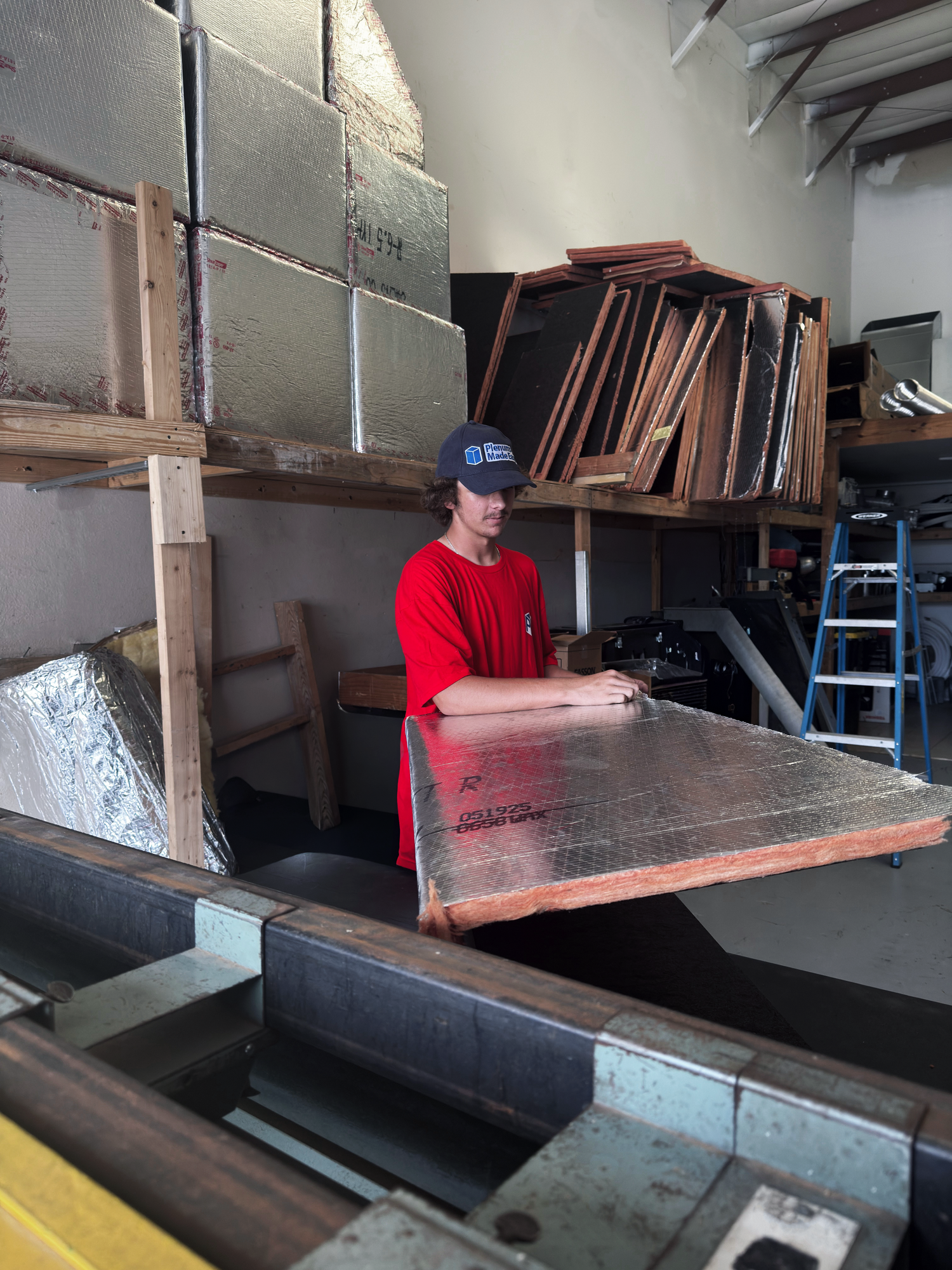 Person in a Plenums Made Easy shirt working with fiberglass duct board in a workshop.